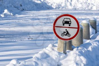 Sign stating No entry for cars or motorcycles - standing in the snowdrift