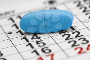 Blue medicine pill on the monthly calendar background. Medicine concept of viagra, medication for stomach, erection, sleeping. February 14th - love day.