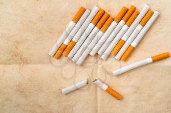 Broken cigarettes on old paper background, stop smoking concept