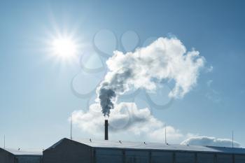 Factory pipe polluting air, smoke from chimney against sun, environmental problems, ecological theme, industry scene
