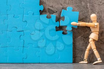 Wooden mannequin building blue puzzle. Creating or building own business concept.