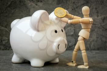 Dummy put coin to piggy bank, concept saving money for the future