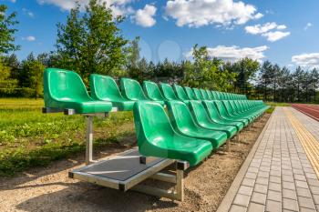 Two rows of green plastic seats on the school stadium