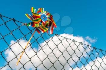 Colorful pinwheel on the metal fence with summer sky background