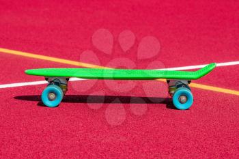 Green penny skateboard on the sports ground, summer outdoors