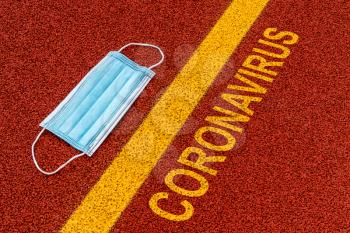 Medical disposable face mask on the ground with yellow line and message CORONAVIRUS
