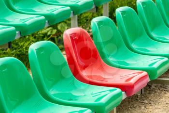 One red seat among different color (green) seats in a stadium (UNIQUE / CONFIDENCE CONCEPT)