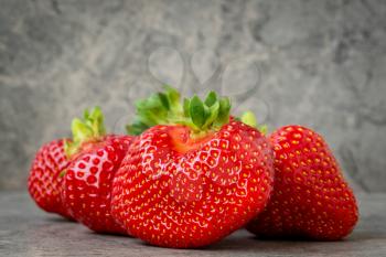 Pile of strawberries on a grey stone background. Selective focus 