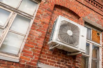 Air conditioning unit on the facade of a old red brick house