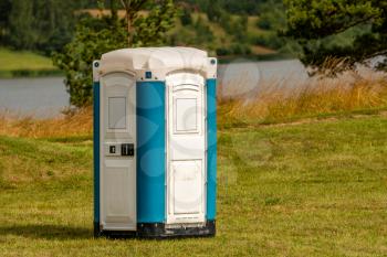 Portable plastic toilet on the meadow with a lake in background