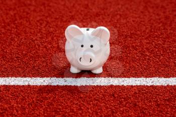 Piggy bank on starting line in the stadium. Concept sport funds and finances