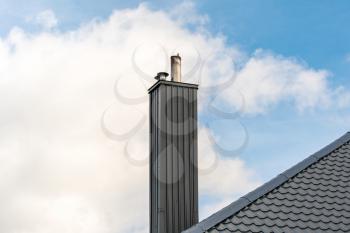 Roof of a detached house with a chimney against the sky