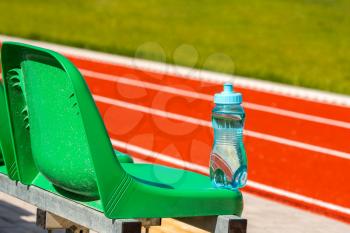 Sport water bottle on the green seats of sports ground