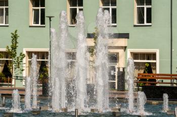 Fountain and water jets on a bright sunny day in a city square