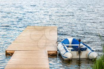 Inflatable motor boat moored to a wooden pier on the lake