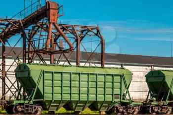 Green loading railway wagon standing near the elevator. Grain silo, warehouse or depository is an important part of harvesting.