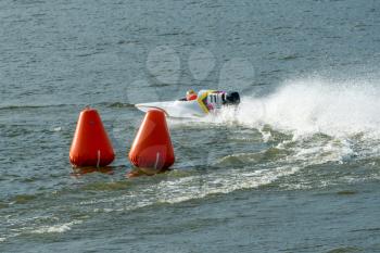 Powerboat go fast along the lake and rounding a marker buoy in a race. Focus on orange buoy.