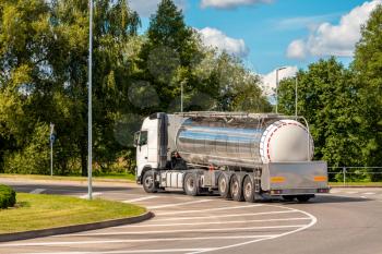 White truck with chrome tanker on a roundabout road in sunny and summer season
