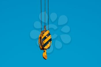 Large yellow crane hook on lifting gears for lifting loads on a background of blue sky. Construction concept.