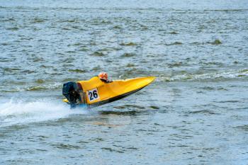 Yellow powerboat with number 26 go fast along the lake at powerboat racing