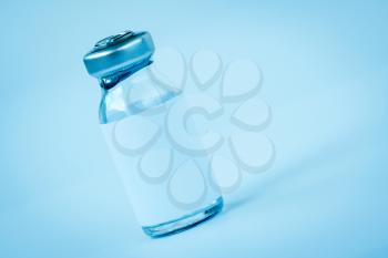 Close up of medical bottle with vaccine or medicine. Blue toned image.