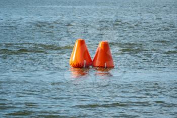 Two inflatable orange buoys in a lake. Safety in a water.