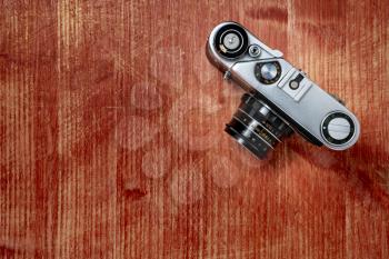 Old vintage camera on wooden background, top view, flat lay with copy space. Concept for the photographer, old photographic equipment, minimalistic style.