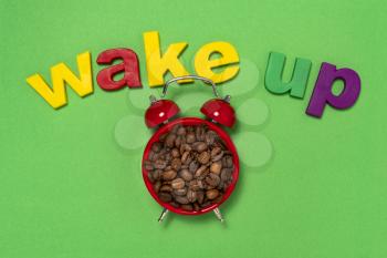 Good morning coffee and alarm clock concept. Coffee beans in retro alarm clock with word wake up