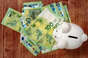 White piggy bank on money, euros bills. Top view. Financial savings concept.
