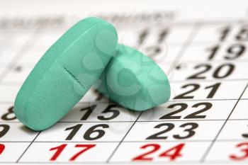 Medical pills on a  calendar sheet with dates and numbers. Improper administration of tablets at one time is dangerous for health