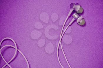 Flat lay concept: headphones on pastel backgrounds. Purple headphones on a purple background, top view, copy space. Trendy colorful photo. Minimal style.
