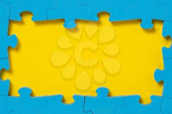 The frame from blue puzzle on yellow background with copy space