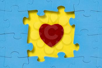 Red heart placed in a center of blue puzzle.Find love. 