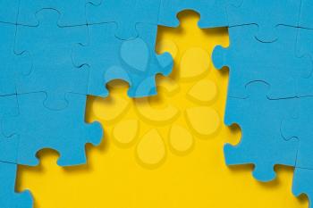 Unfinished blue jigsaw puzzle on yellow background with copy space. Business strategy teamwork and problem solving concept. Teamwork is collaborative effort of team to achieve goal or complete task. 