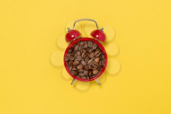 Morning coffee and alarm clock concept. Coffee beans on alarm clock face.