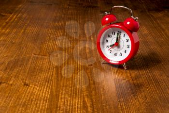 Old fashioned red alarm clock on the old wooden table background