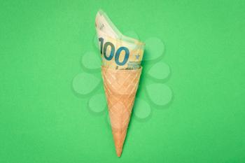 Ice cream wafer cone with one hundred euros banknotes