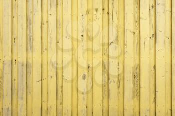 Wall made of yellow painted wooden planks. Wall of vertical old boards.