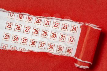 Red paper torn to reveal lottery ticket numbers. Conceptual image.