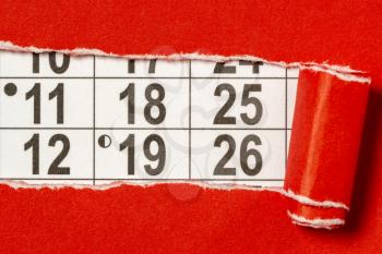 Red paper torn to reveal monthly calendar.Conceptual image.