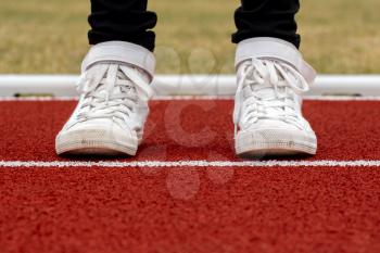Close-up on child feet with sneakers on the running track
