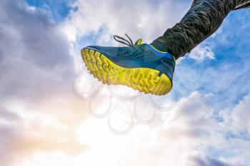 Running and jumping over the camera. Running shoe on sky background,  view from below