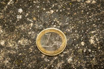One Euro coin dropped on the pavement. The coin of one euro found on a road