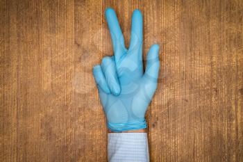 Male doctor hand in blue glove make gesture. Concept of protection against pandemic and viruses.