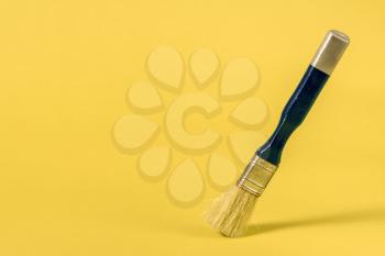 Paint brush stands on the yellow background, copy-space