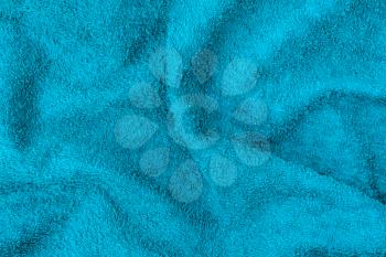 Undulating blue plush bath towel fabric. Blue fabric and texture concept - close up of a towel terry cloth or terry textile background