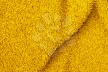 Undulating plush bath towel fabric. Yellow fabric and texture close-up. May be used as background.