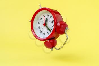 Red  alarm clock floating on the air with yellow color background