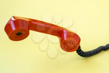 Retro orange telephone receiver on yellow background. Communication concept.