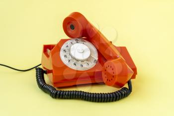 Retro orange telephone on yellow background. Communication concept.